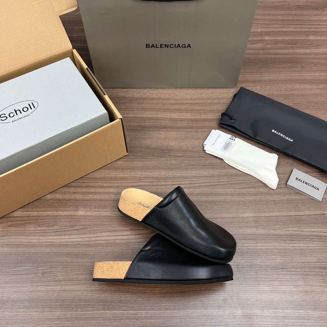 Black slip-on slide sandals with tan cork footbed, angled side view