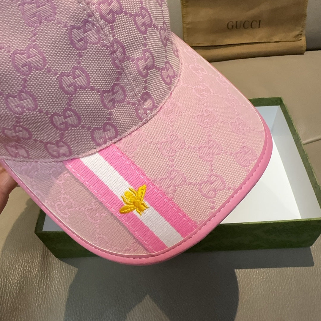 Gucci pink cap close-up showing GG monogram, striped band, and gold bee