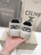 White sneakers with black heel panels and bold 'SNEAKERS' lettering