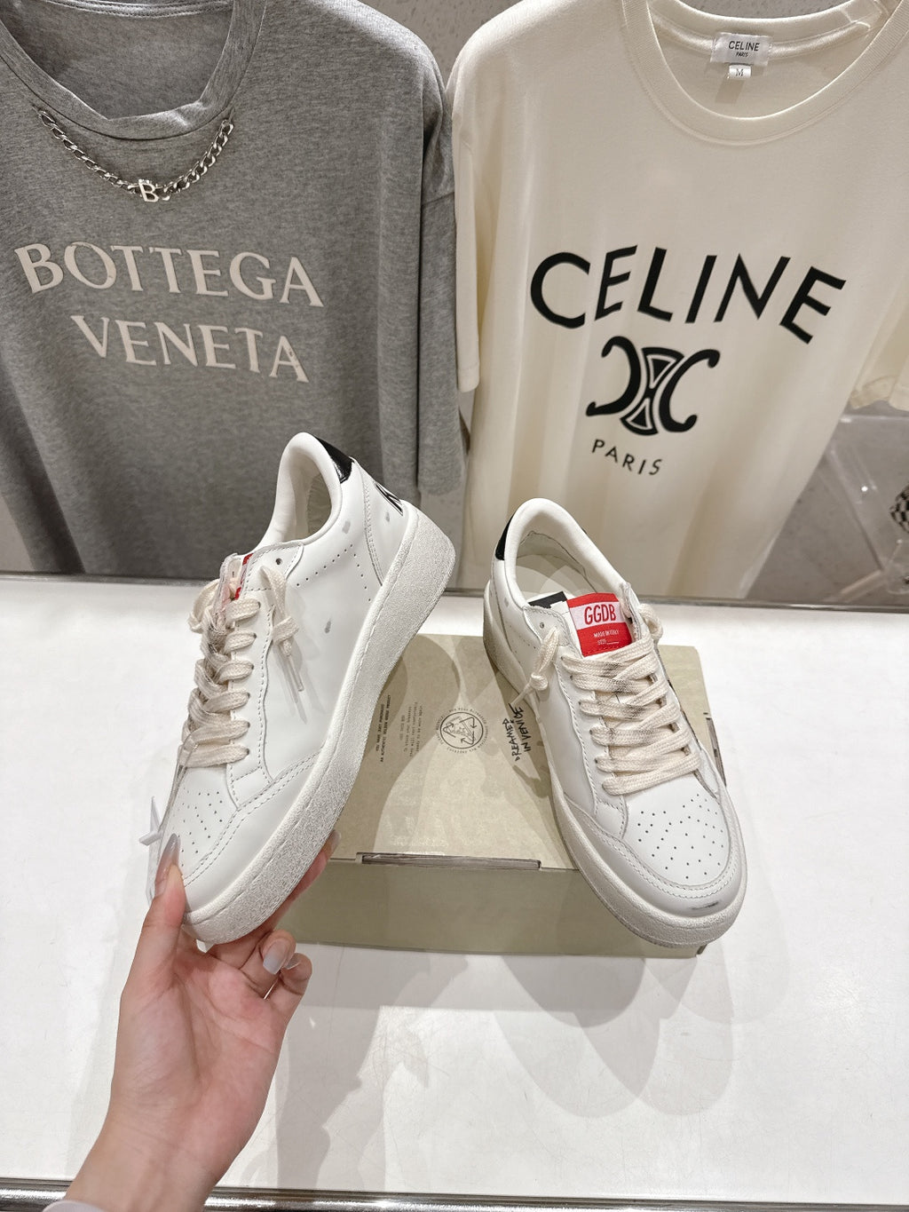 White lace-up sneakers with leopard side trim, held up beside another pair