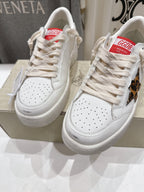 Pair of white lace-up sneakers with perforated toe and textured rubber sole