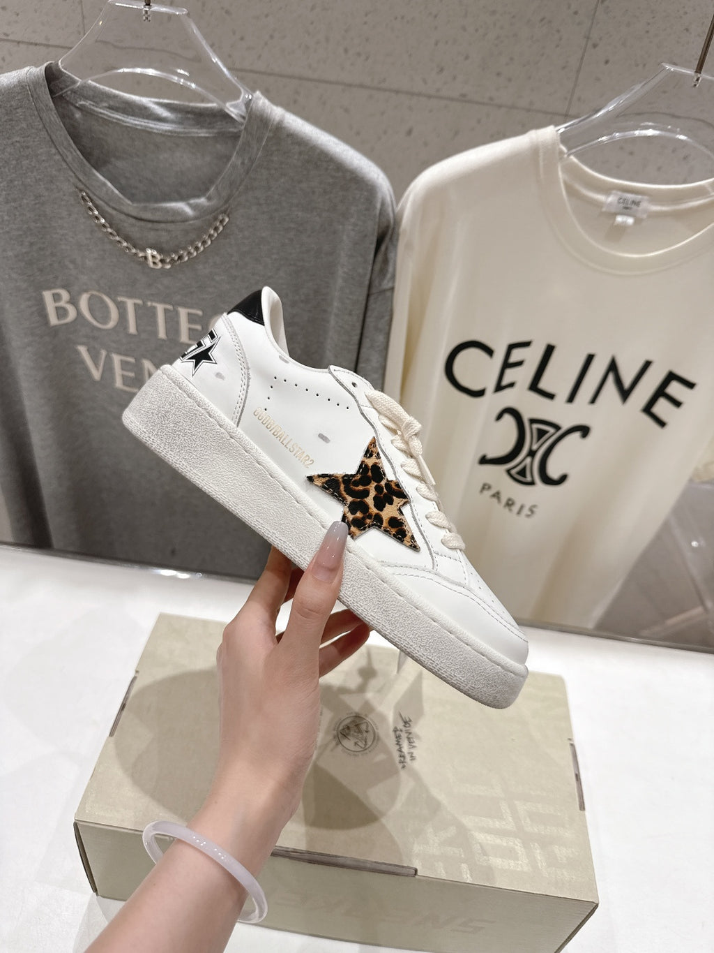 White lace-up sneakers with leopard side trim and small black detail near laces