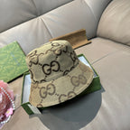 Tan bucket hat with dark GG monogram pattern and curved brim, handheld view