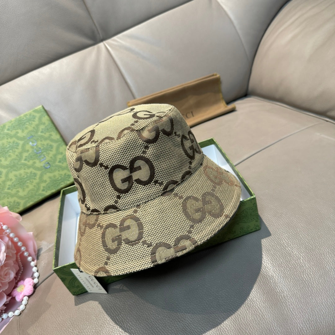Tan bucket hat with dark GG monogram pattern and curved brim, handheld view