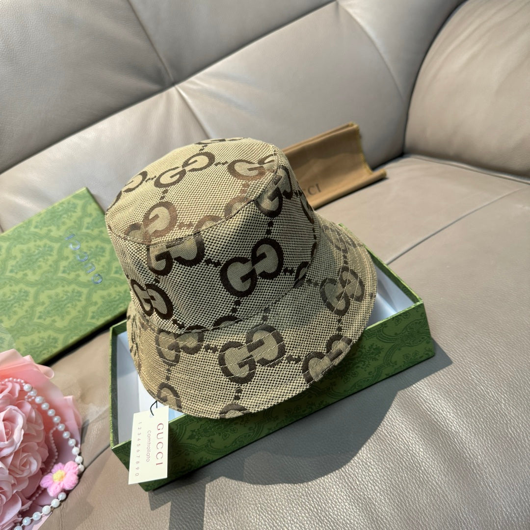 Tan bucket hat with dark GG pattern and curved brim, shown from front angle