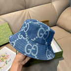 Gucci blue denim bucket cap with white GG logo monogram repeat, angled view.