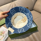 Gucci blue GG-print bucket cap with white inner lining and adjustable strap tags.