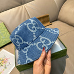Gucci blue bucket cap with white GG pattern, front view held in hand.