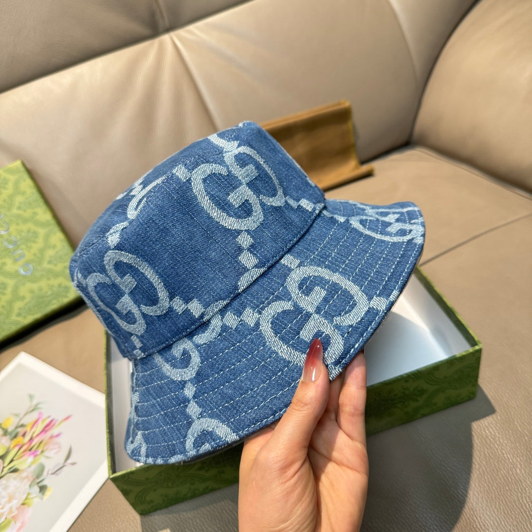 Gucci blue bucket cap with white GG pattern, front view held in hand.
