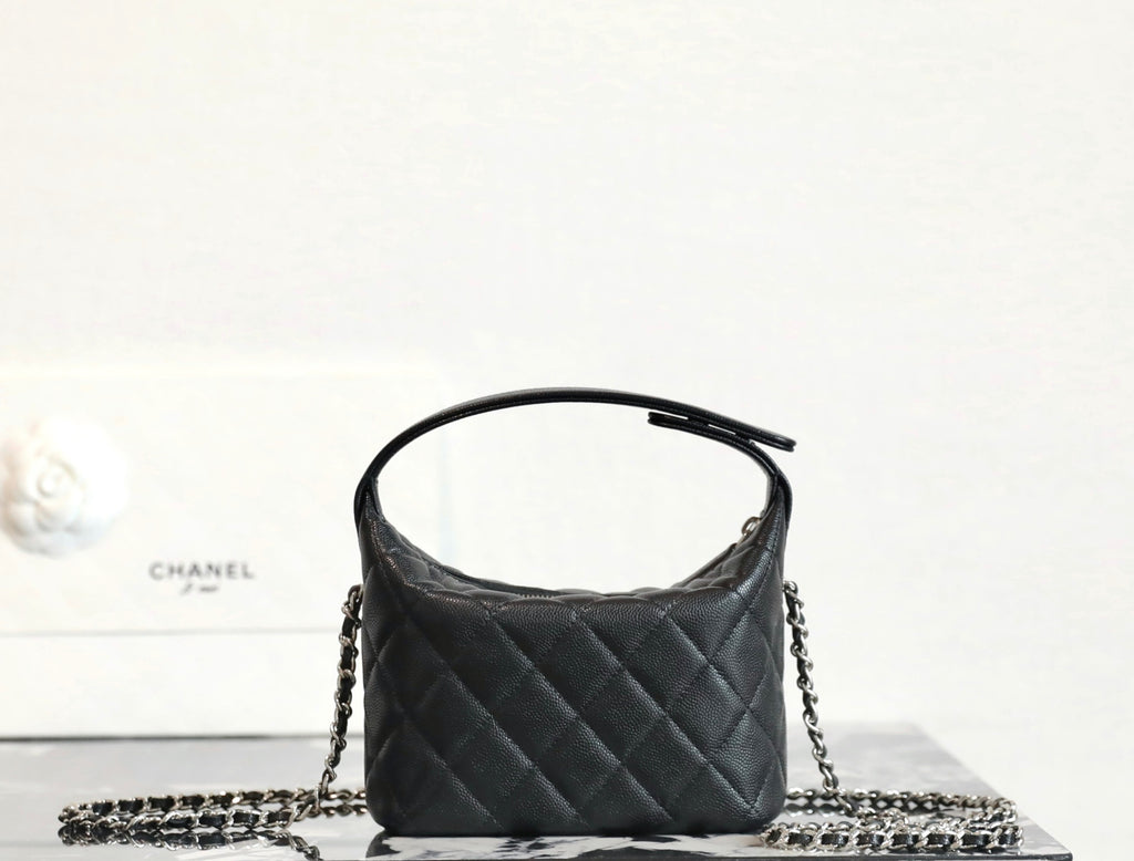 Black quilted handbag with top handle and silver chain strap, rounded top