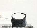 Black quilted handbag with top handle and silver chain strap, rounded top