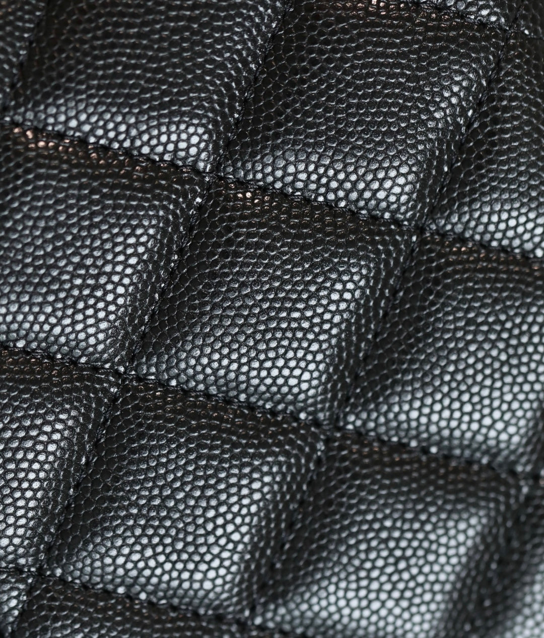 Quilted black leather handbag texture detail with diamond stitching