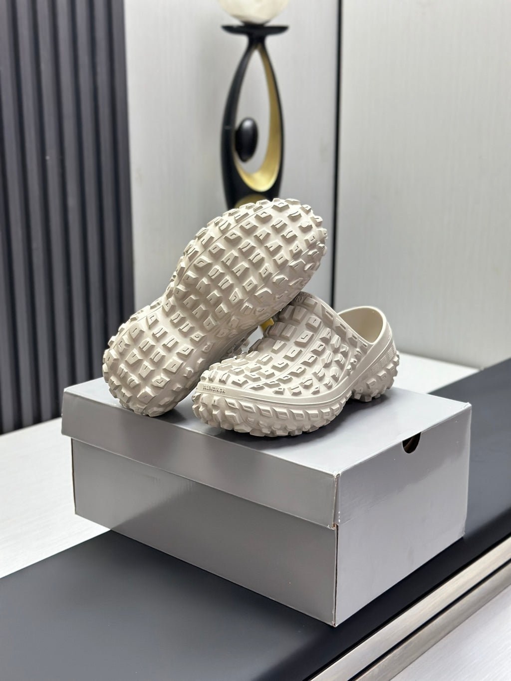 Balenciaga white textured slide sandals pair on box, one shoe placed over the other