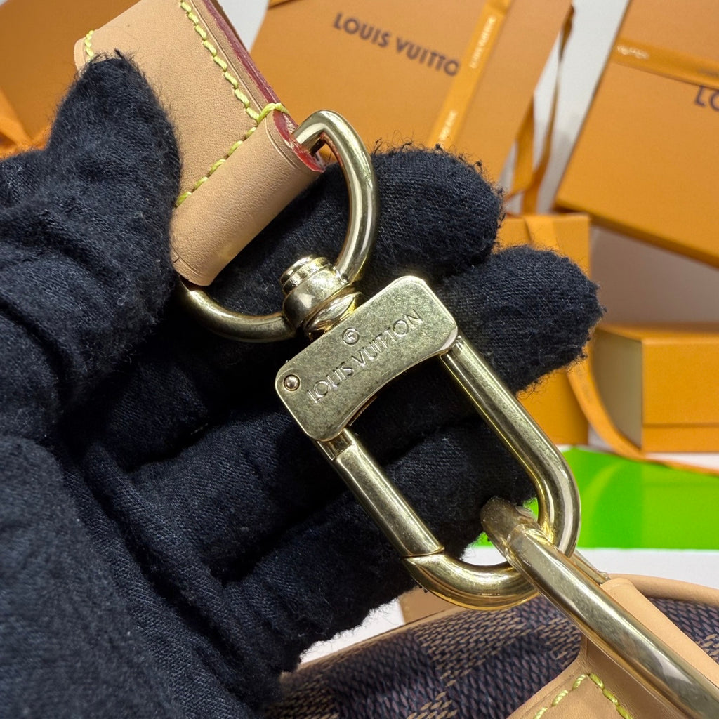 Louis Vuitton mini bag with metal clasp and engraved charm on navy fabric strap