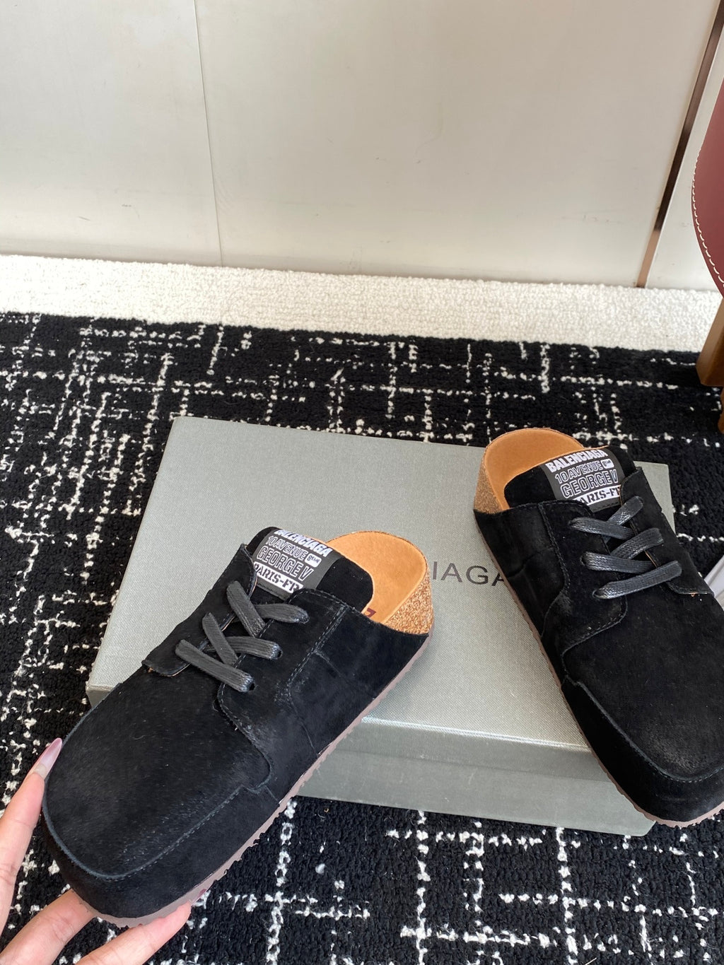 Black suede lace-up sneakers with tan lining, placed on shoebox
