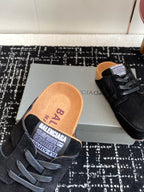 Black suede lace-up sneaker showing branded tan insole and orange heel