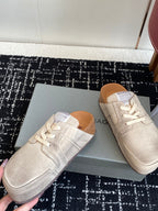 Two light tan lace-up sneakers on a box, front and toe views