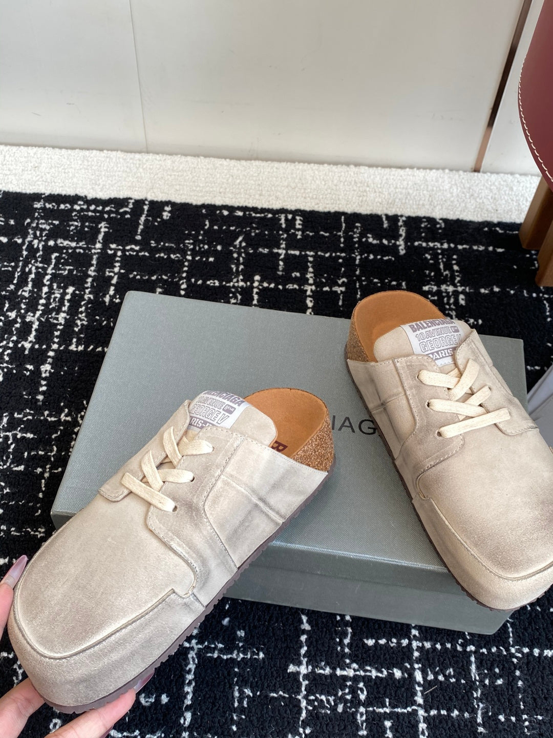 Two light tan lace-up sneakers on a box, front and toe views