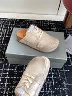 Light tan lace-up sneakers on a box, one shoe angled upward