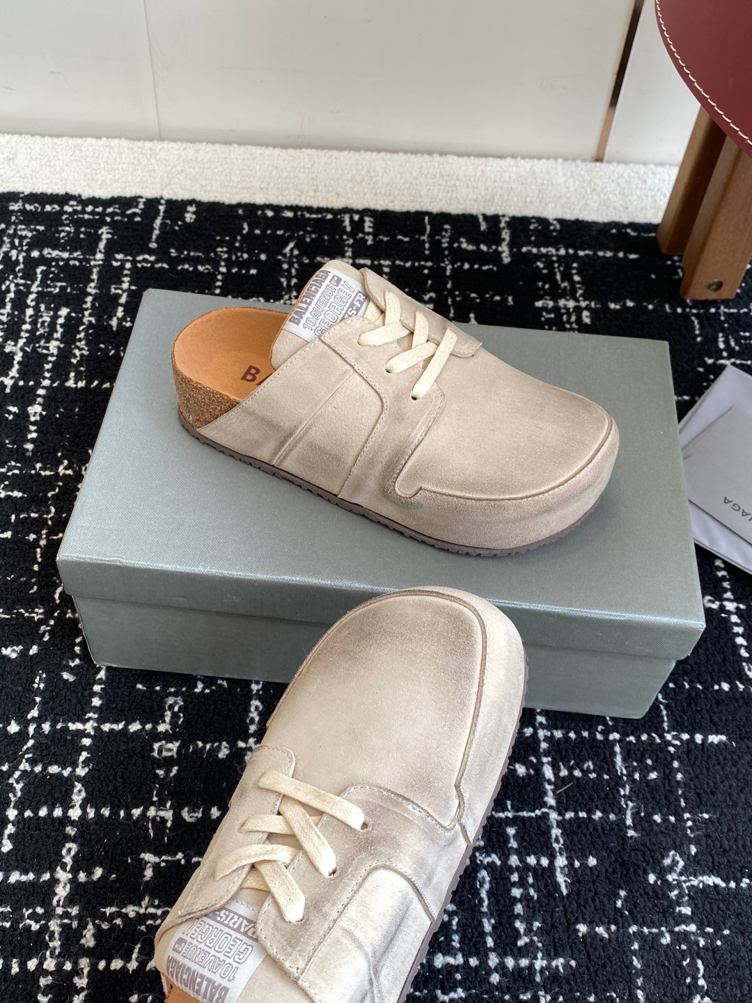 Light tan lace-up sneakers on a box, one shoe angled upward