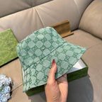 Green GG monogram bucket hat held by hand, showing front panel and button
