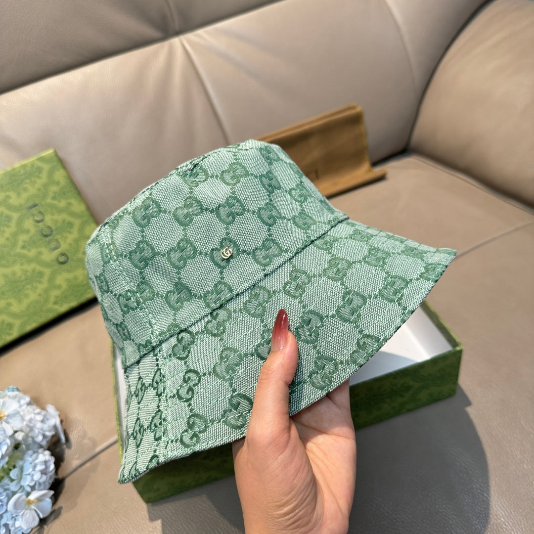 Green GG monogram bucket hat held by hand, showing front panel and button