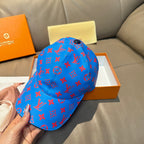 Louis Vuitton cap in bright blue with red monogram pattern and round black top