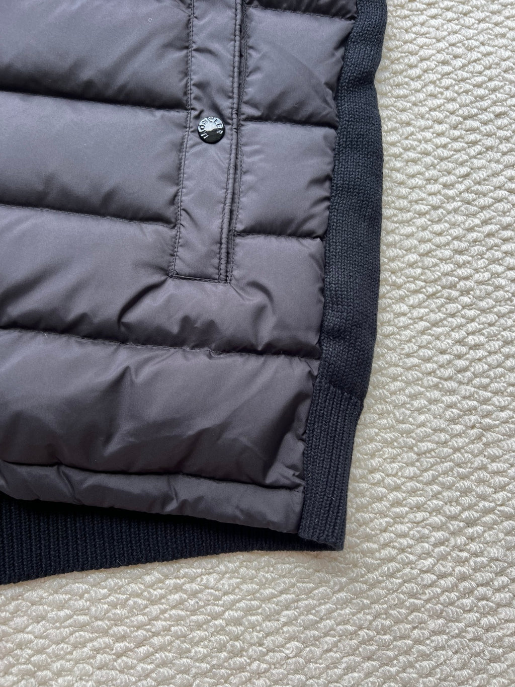 Moncler long puffer jacket hem with front pocket area and zipper pull