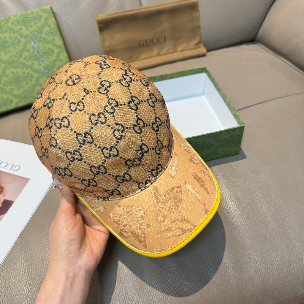Tan GG monogram baseball cap with yellow-trim brim, held in hand