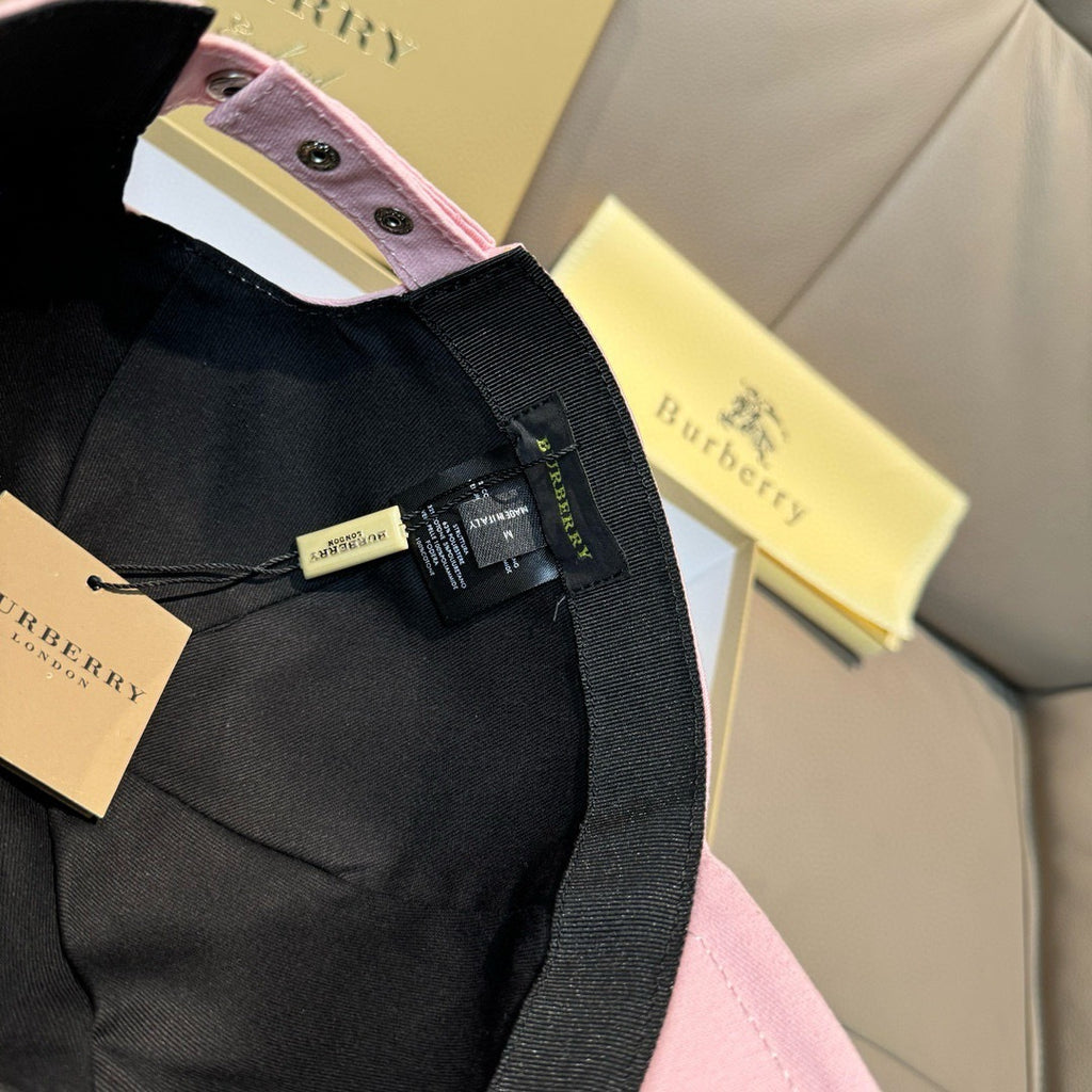 Black strap and product tag on a pink and black baseball cap, adjustable fabric strap