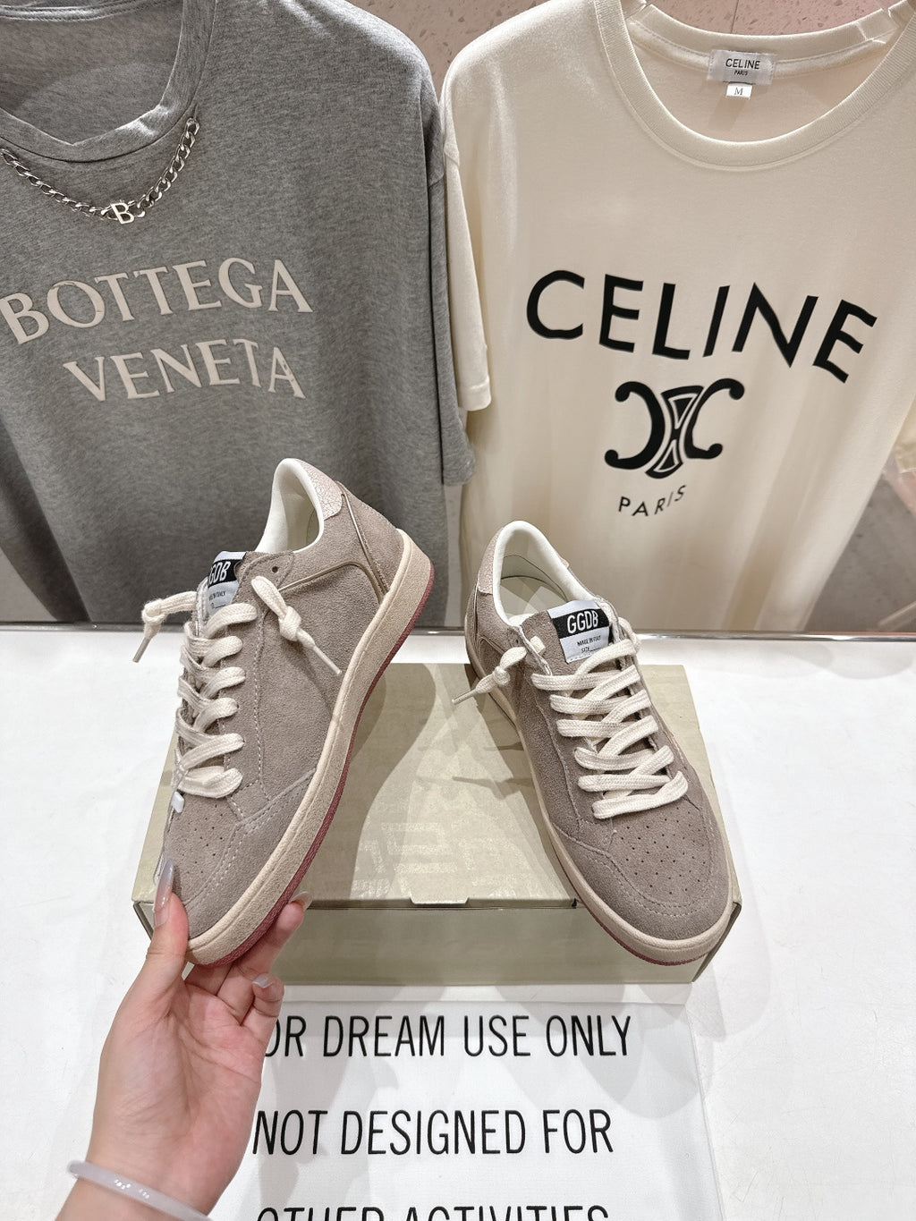 Golden Goose gray low-top sneaker held in hand, lace-up front view