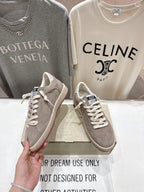 Golden Goose gray low-top sneaker held in hand, lace-up front view