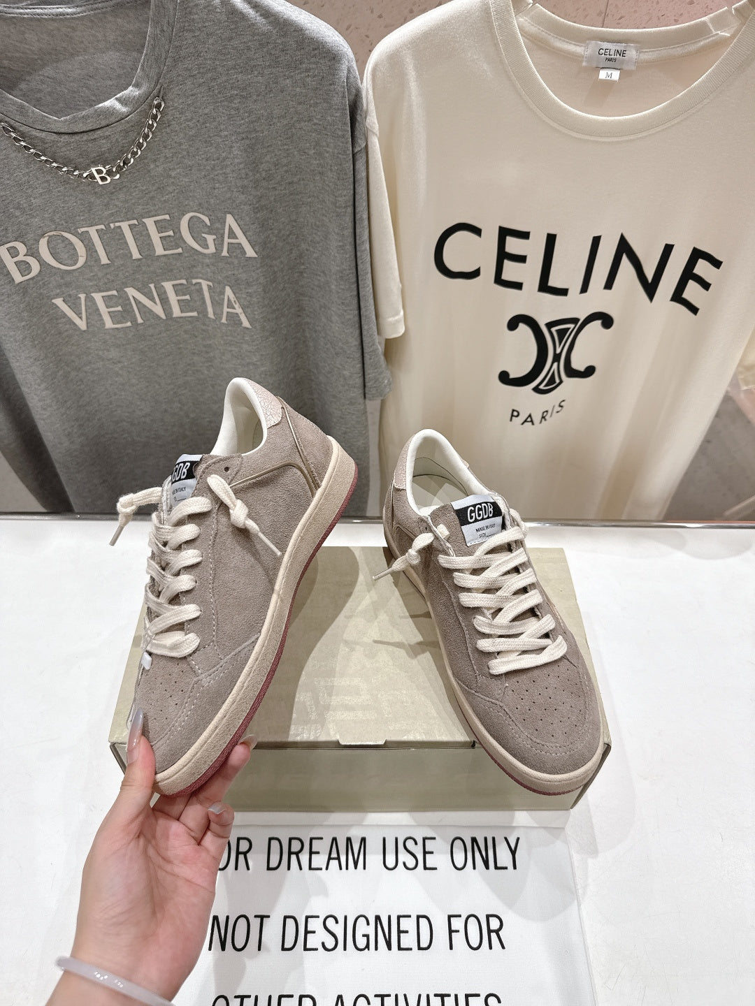 Golden Goose gray low-top sneaker held in hand, lace-up front view
