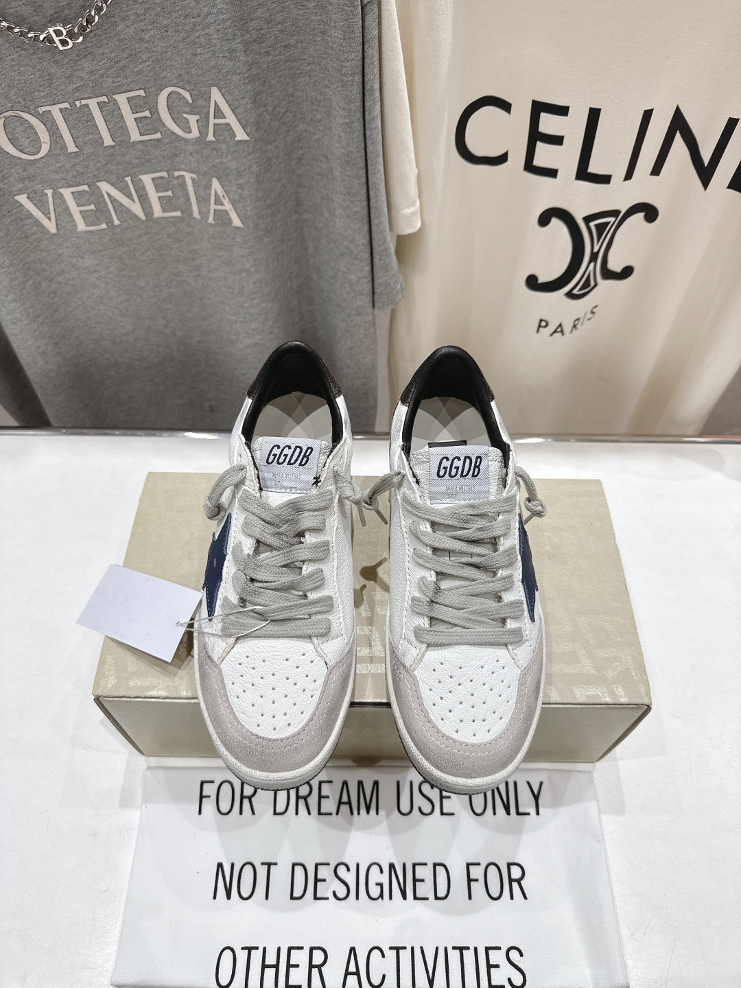 White luxury sneakers with gray laces, perforated toe, and GGD B label on tongue