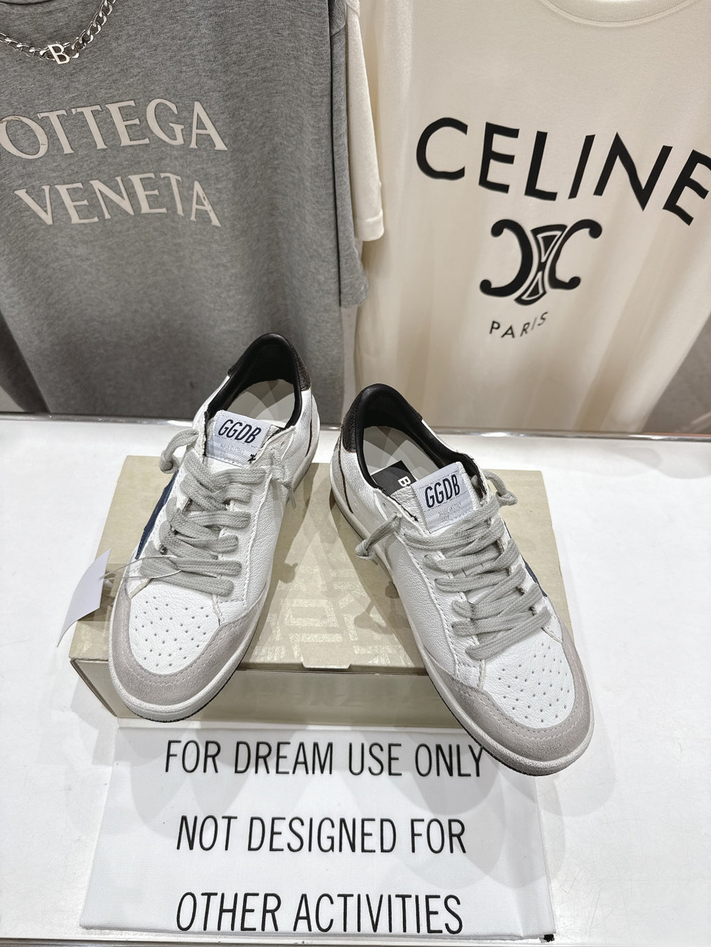 White luxury sneakers with gray laces and perforated toe; GGD B label visible