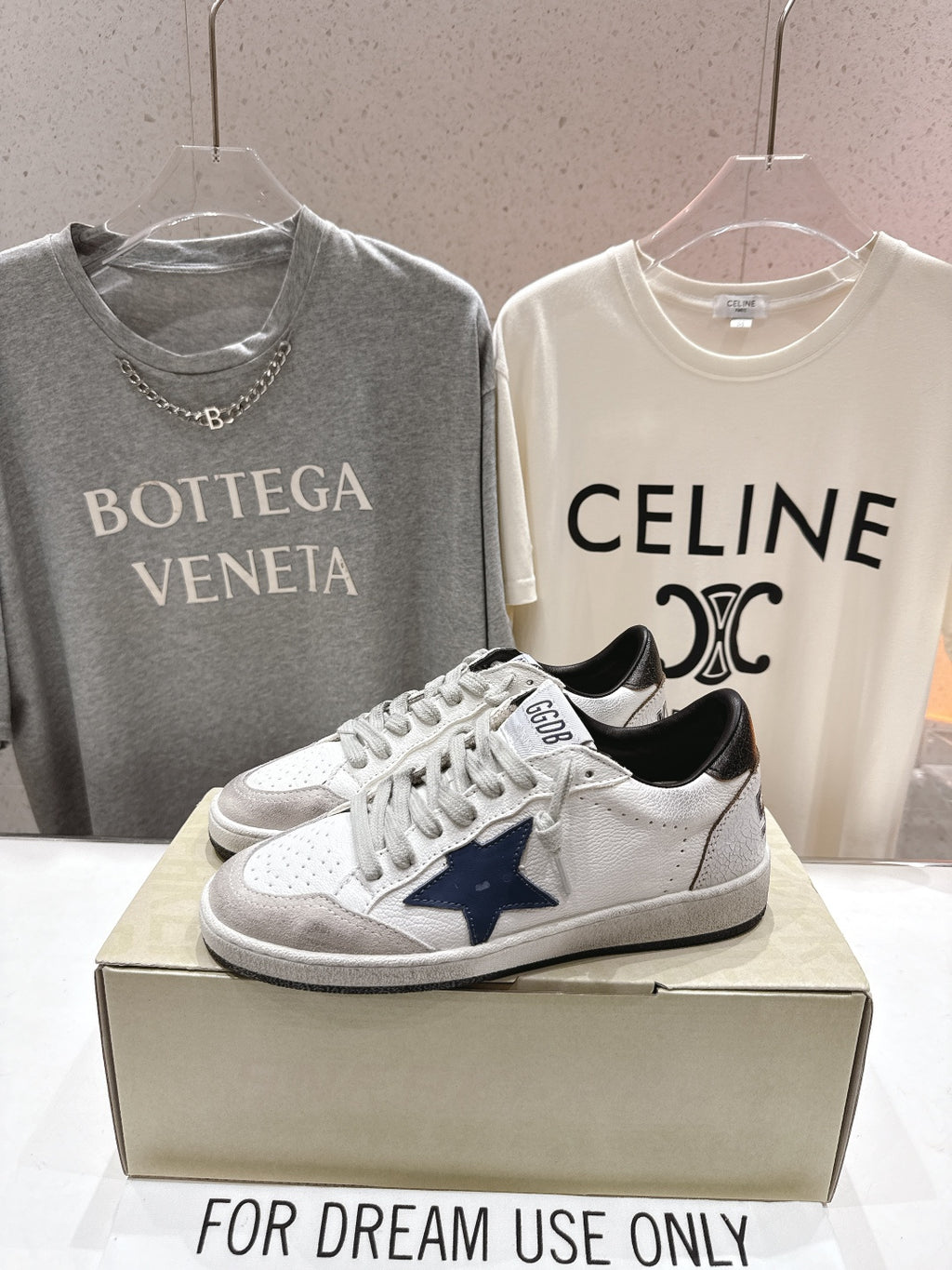 White luxury sneakers with navy star patch, gray laces, and perforated toe