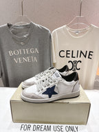 White luxury sneakers with navy star patch, gray laces, and perforated toe