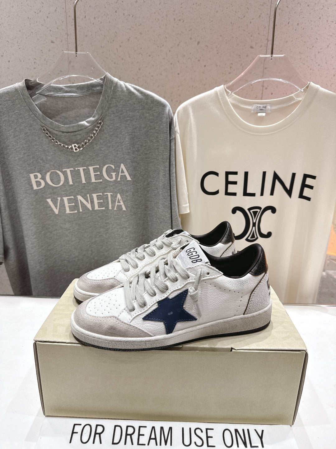 White luxury sneakers with navy star patch, gray laces, and perforated toe