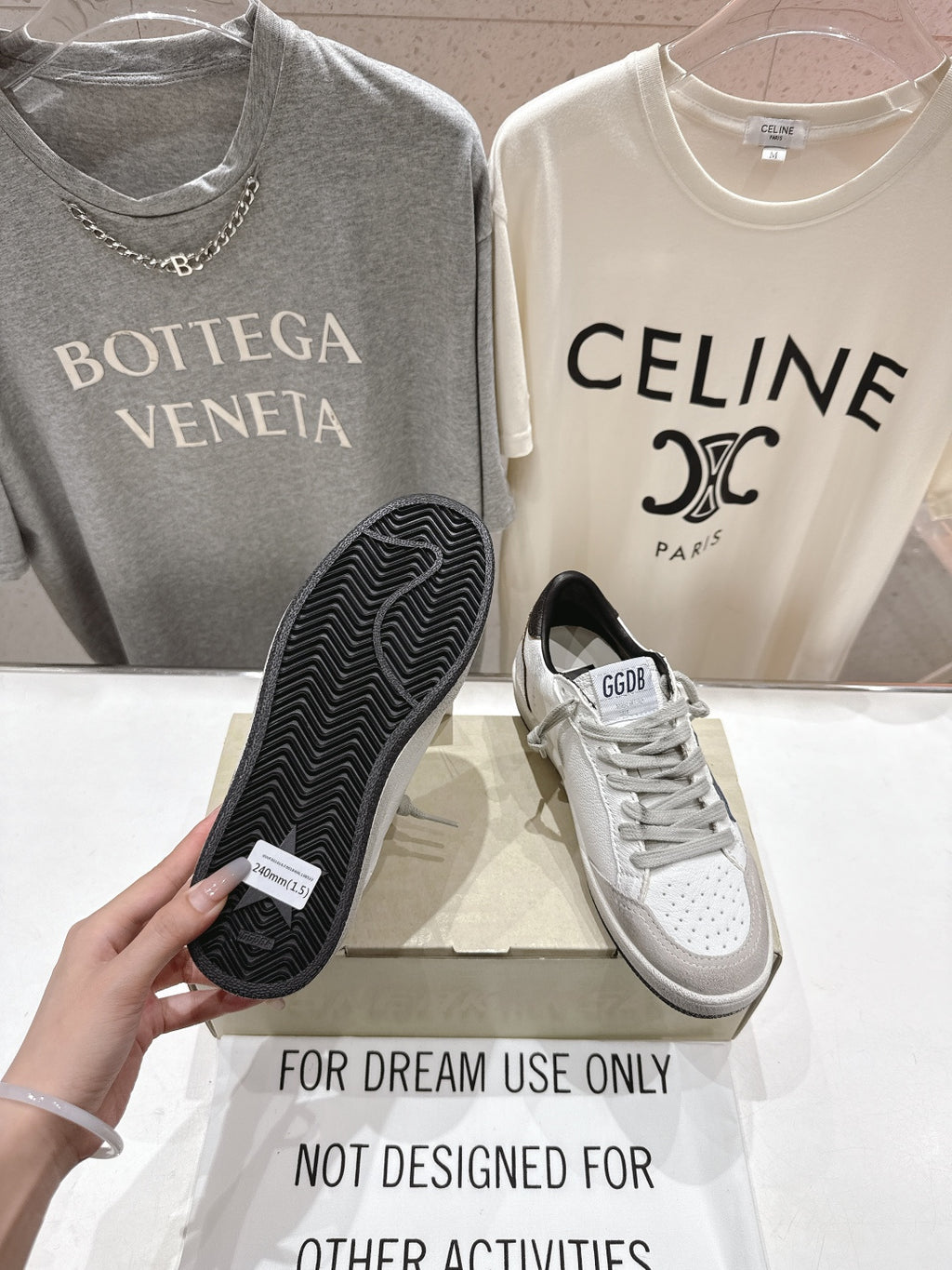 White luxury sneakers with gray laces and perforated toe; tread sole shown