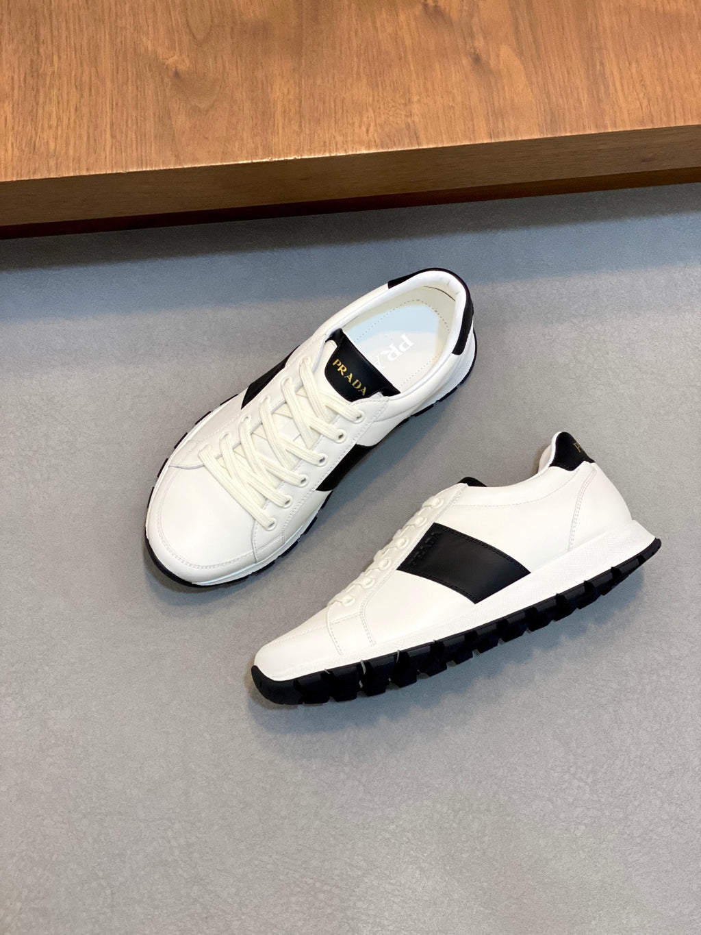 White sneakers on side; black stripe, lace-up front, and rubber tread sole