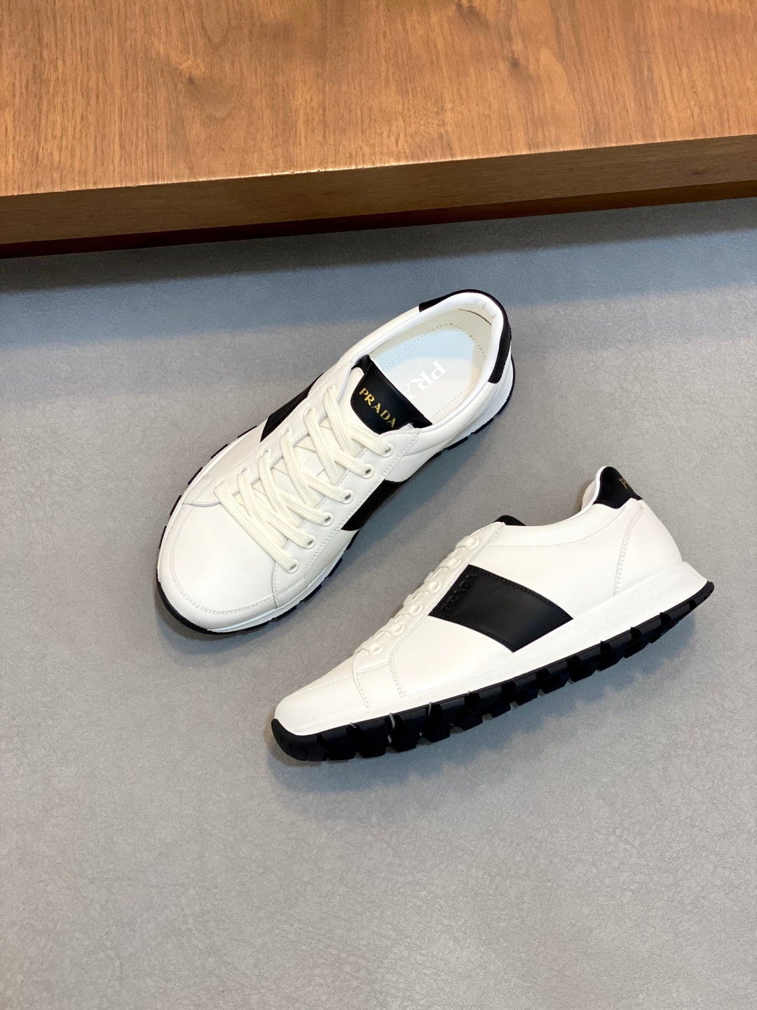 White sneakers on side; black stripe, lace-up front, and rubber tread sole