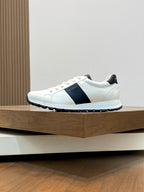 White low-top sneakers with black side band and textured rubber sole