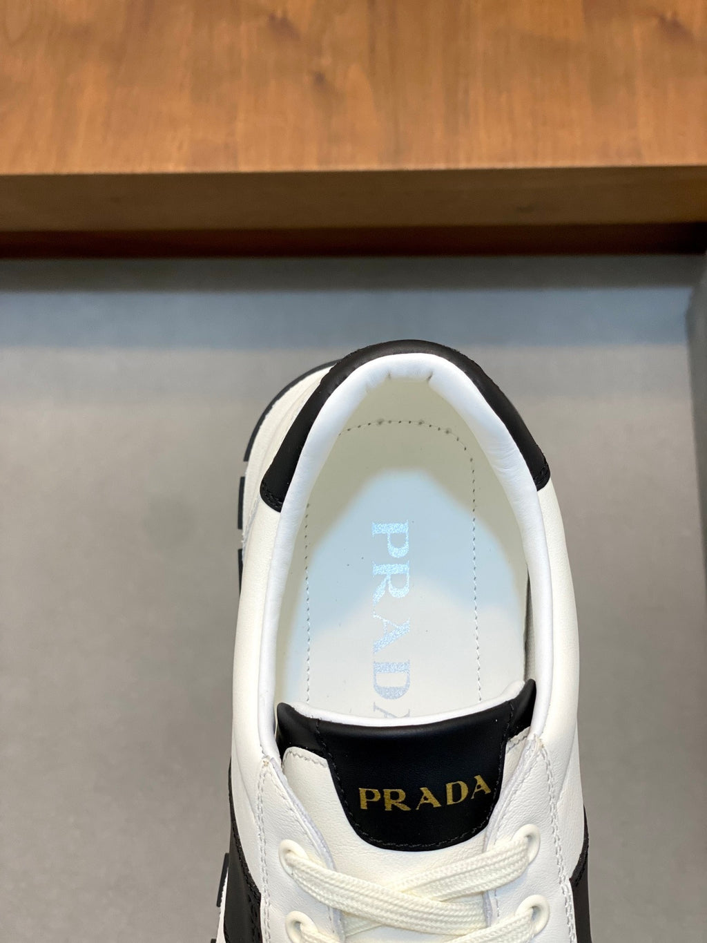 White sneaker interior view with Prada branding on tongue and insole