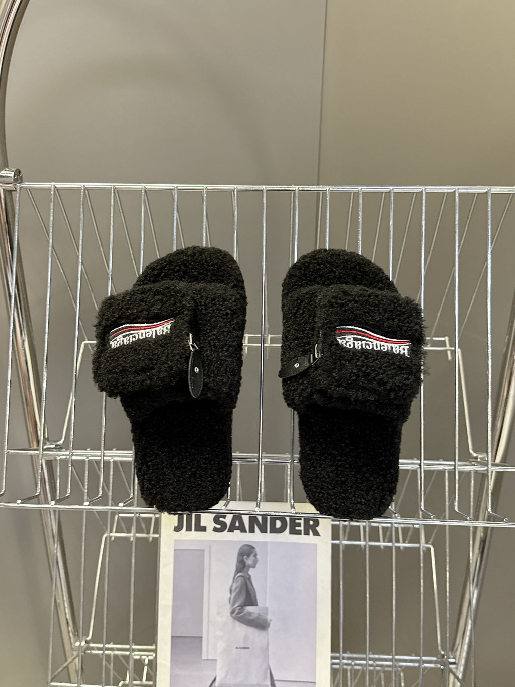 Balenciaga black fuzzy slide sandals on display rack, zipper detail