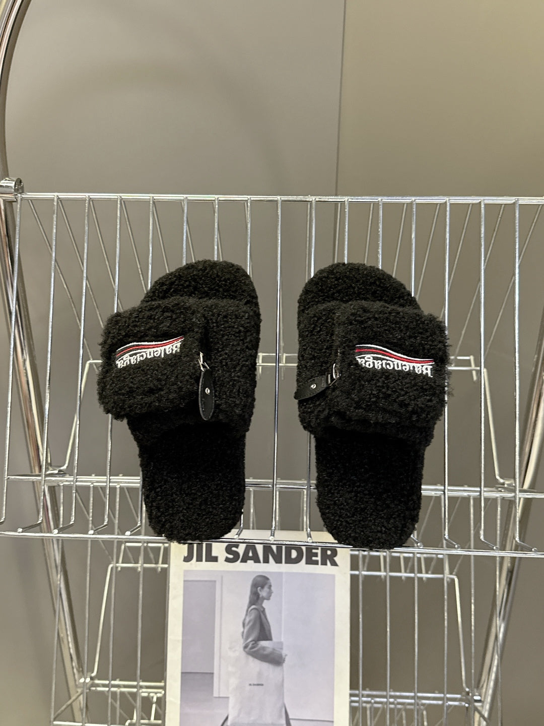 Balenciaga black fuzzy slide sandals on display rack, zipper detail