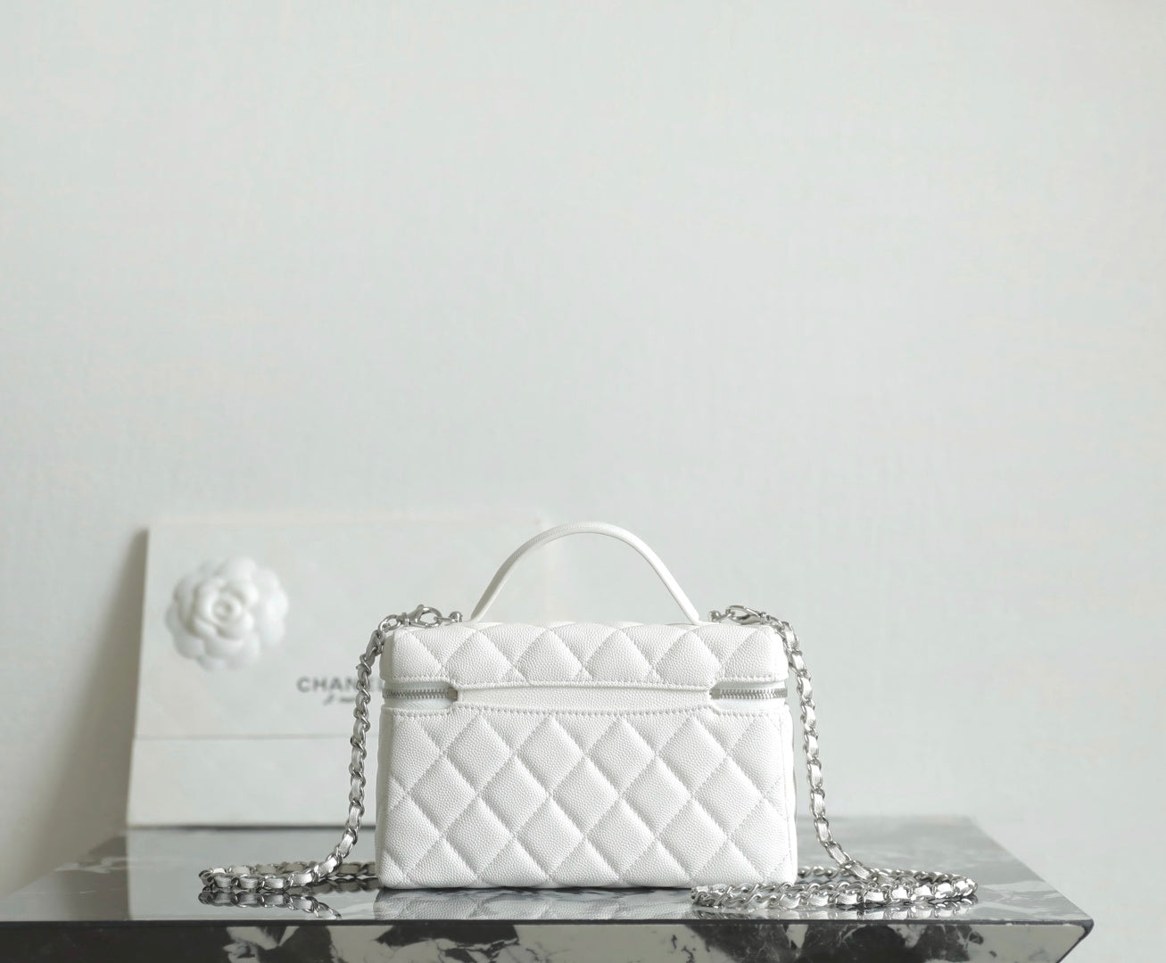 White quilted Chanel mini bag with top handle and chain crossbody strap