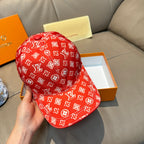 Louis Vuitton red monogram baseball cap with curved brim, shown from side in hand