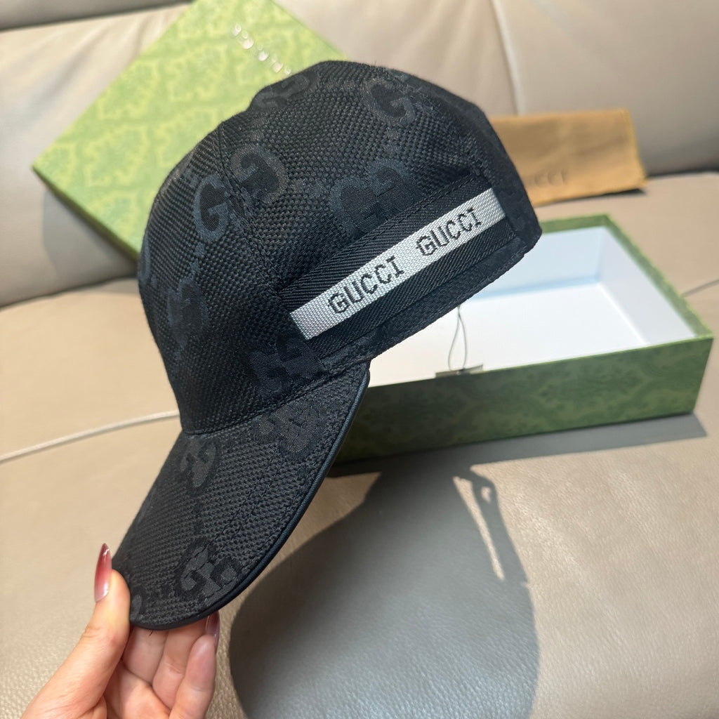 Black Gucci monogram baseball cap with white logo band, held by hand