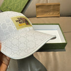 White Gucci baseball cap with GG monogram and The North Face logo patch