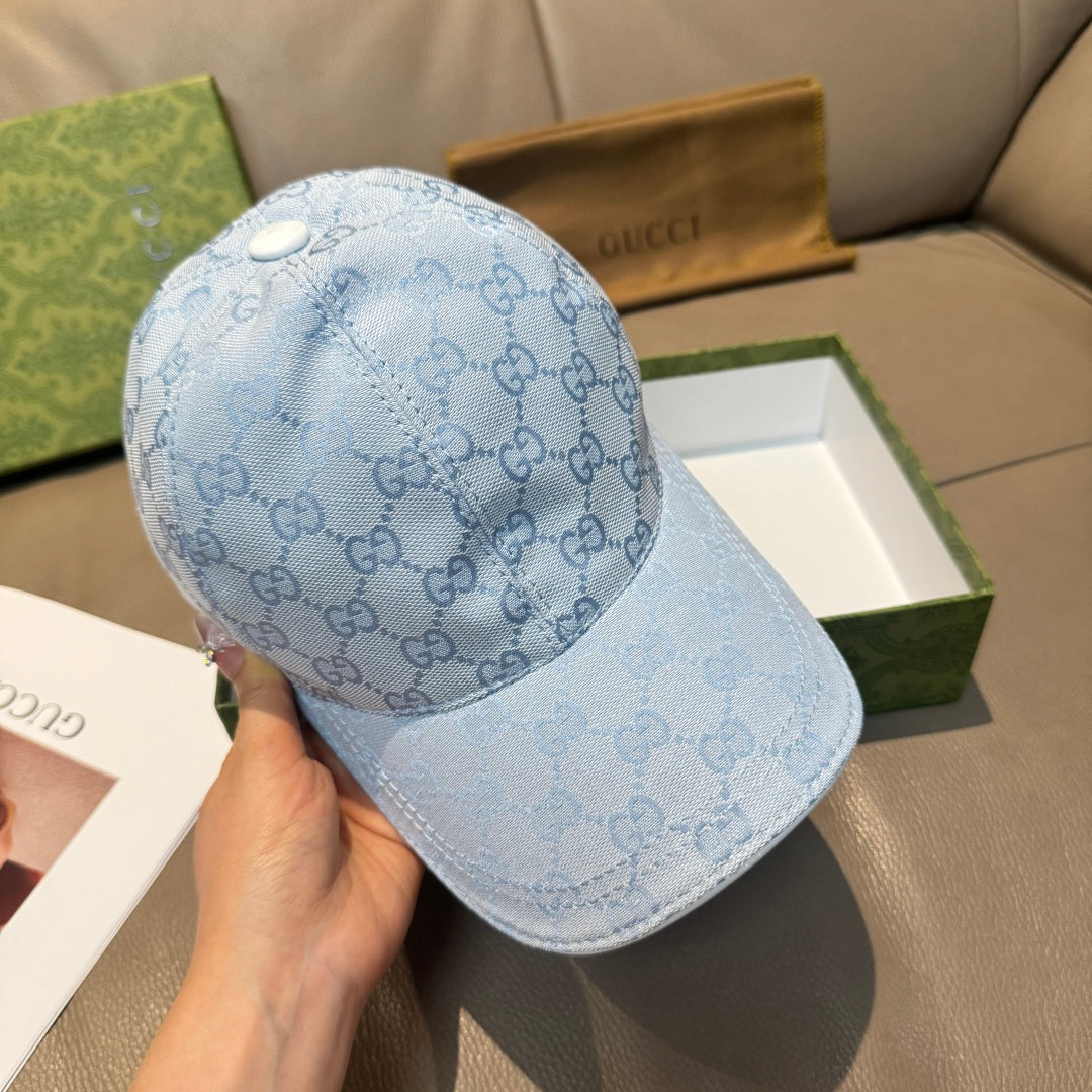Gucci light blue monogram baseball cap held in hand, curved brim